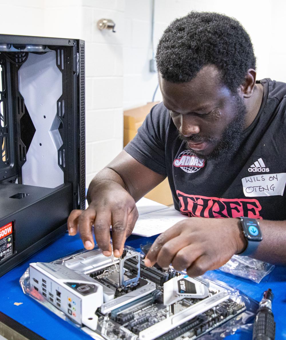 A student works on a computer with exposed hardware in a STEM workshop
