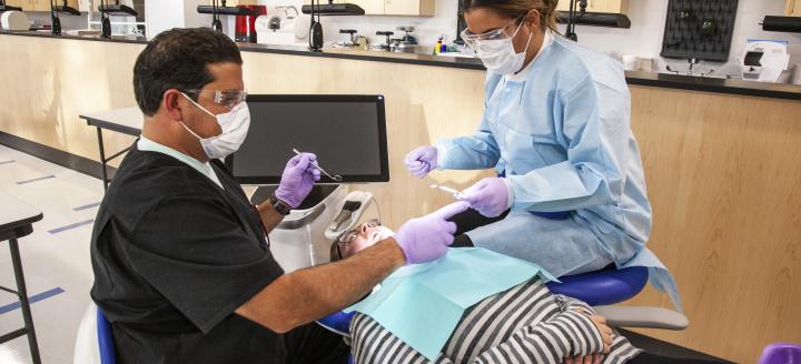 Two dental students attend to a patient