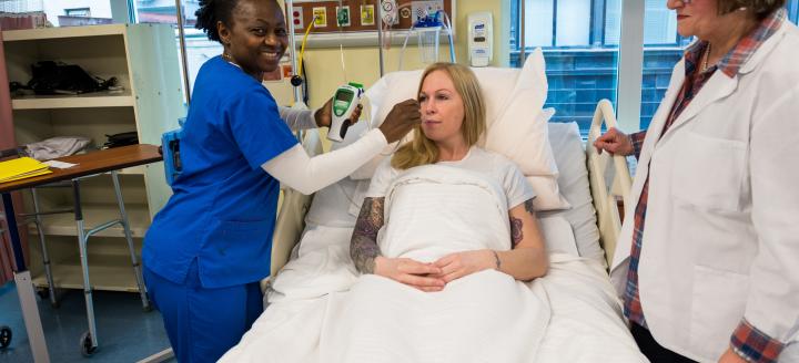 A nurse checks on a patient in a lab setup