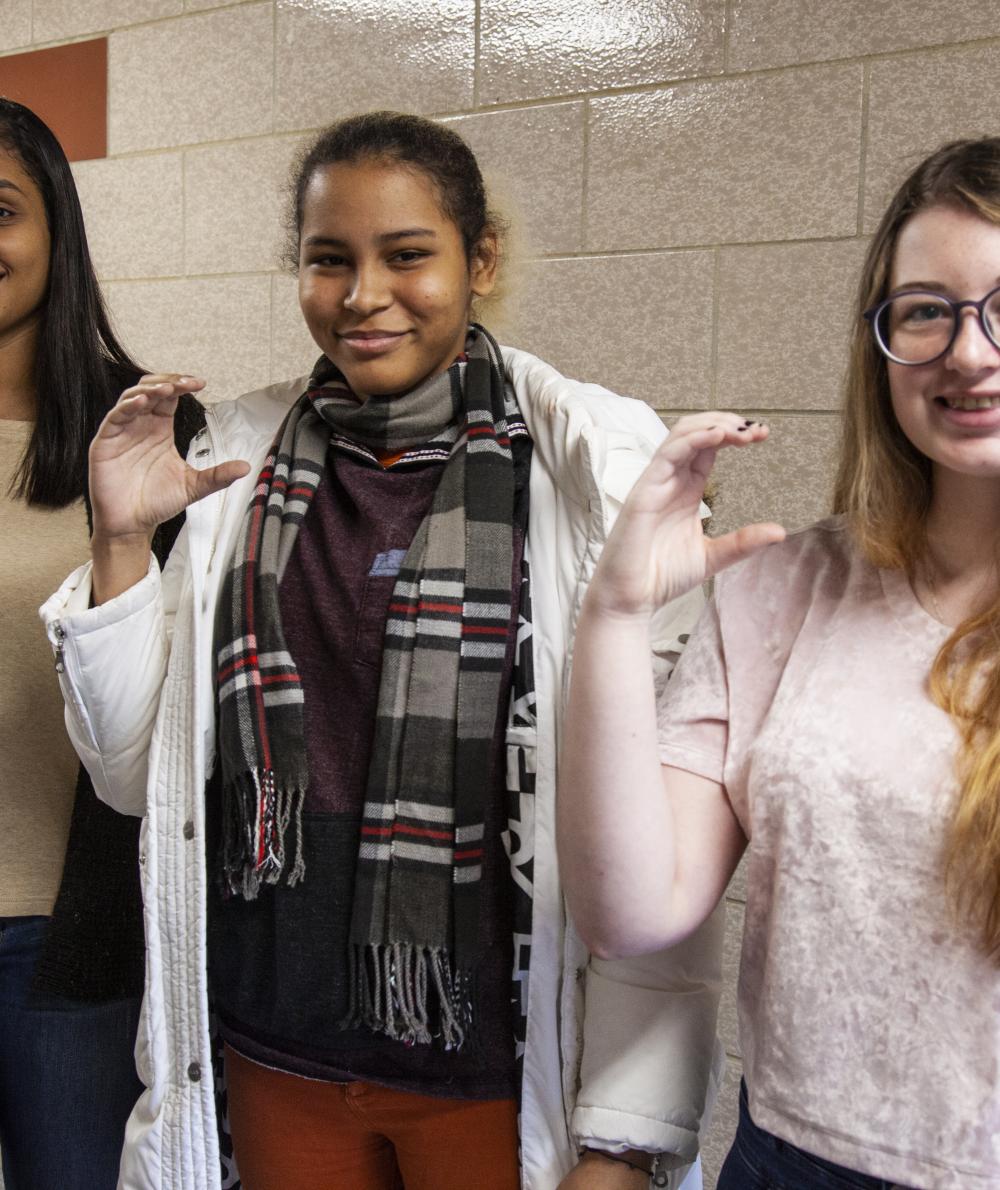Students from the American Sign Language class spell out QCC in sign language