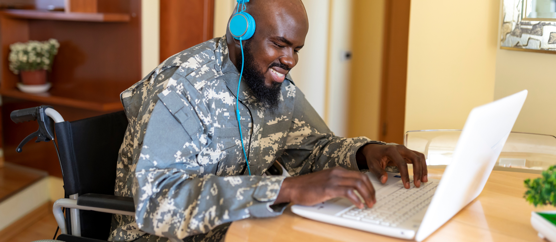 A veteran in a wheelchair uses headphones with a computer