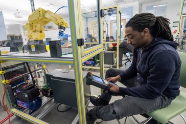 Student works with robot in manufacturing lab