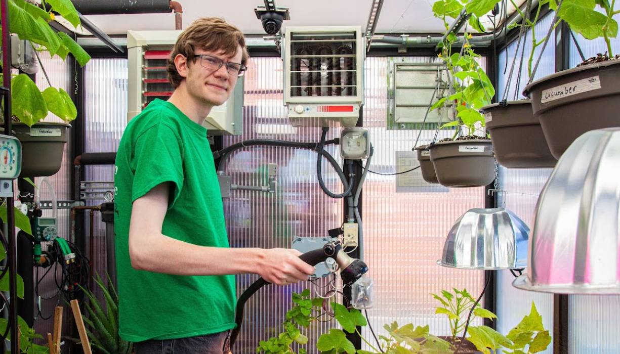 PTK student and Greenhouse volunteer Lucas Sicard waters the plants in the greenhouse.