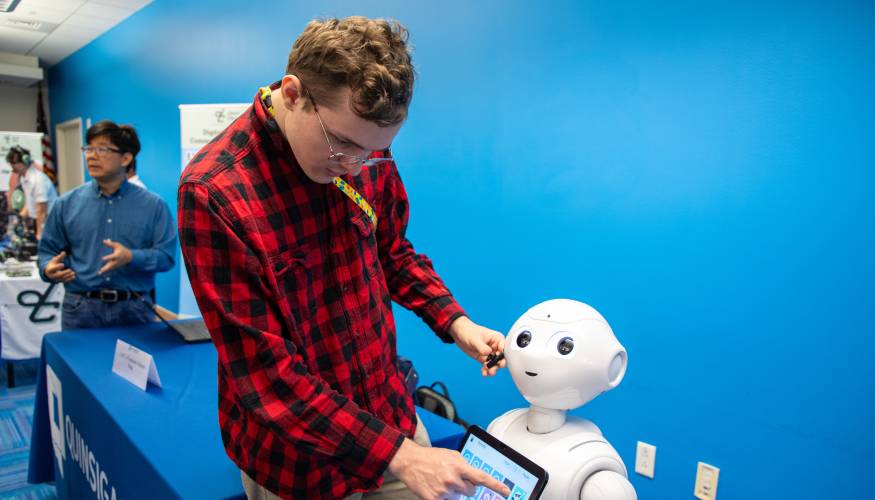 A QCC Computer Science student with Penny the robot.