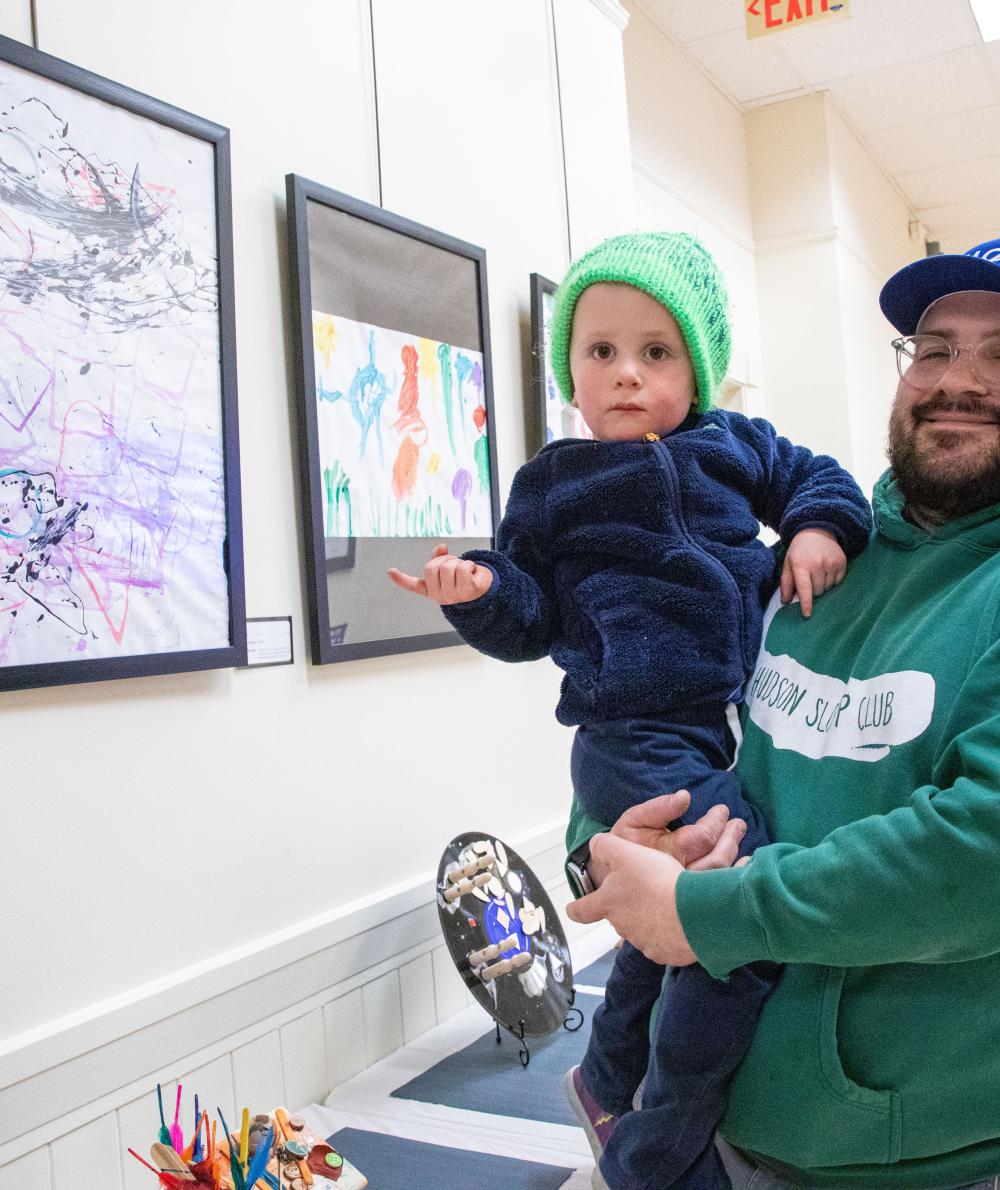 A parent and child look at their display at the Children’s School Art Show