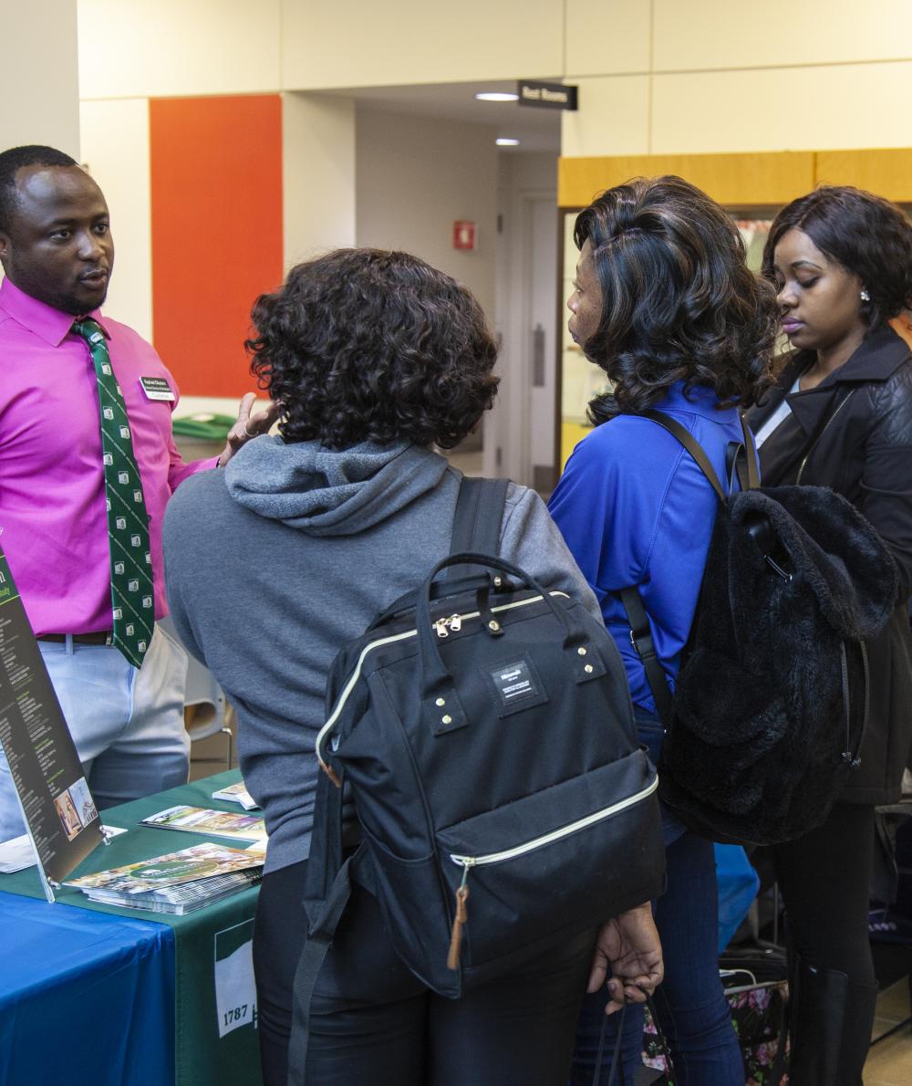 Students check our a booth for another college at a QCC transfer fair