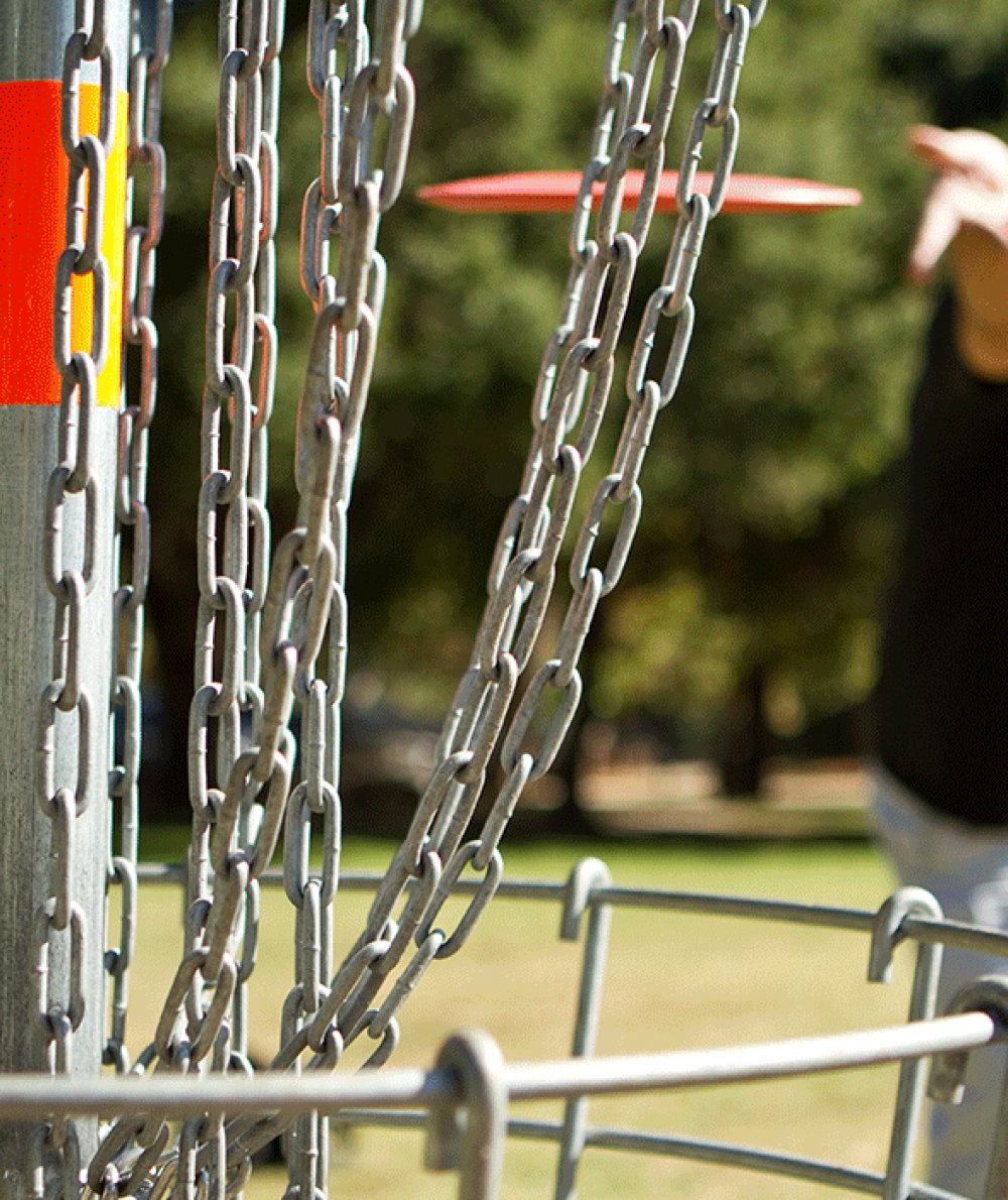 A man throws a frisbee towards the target outside