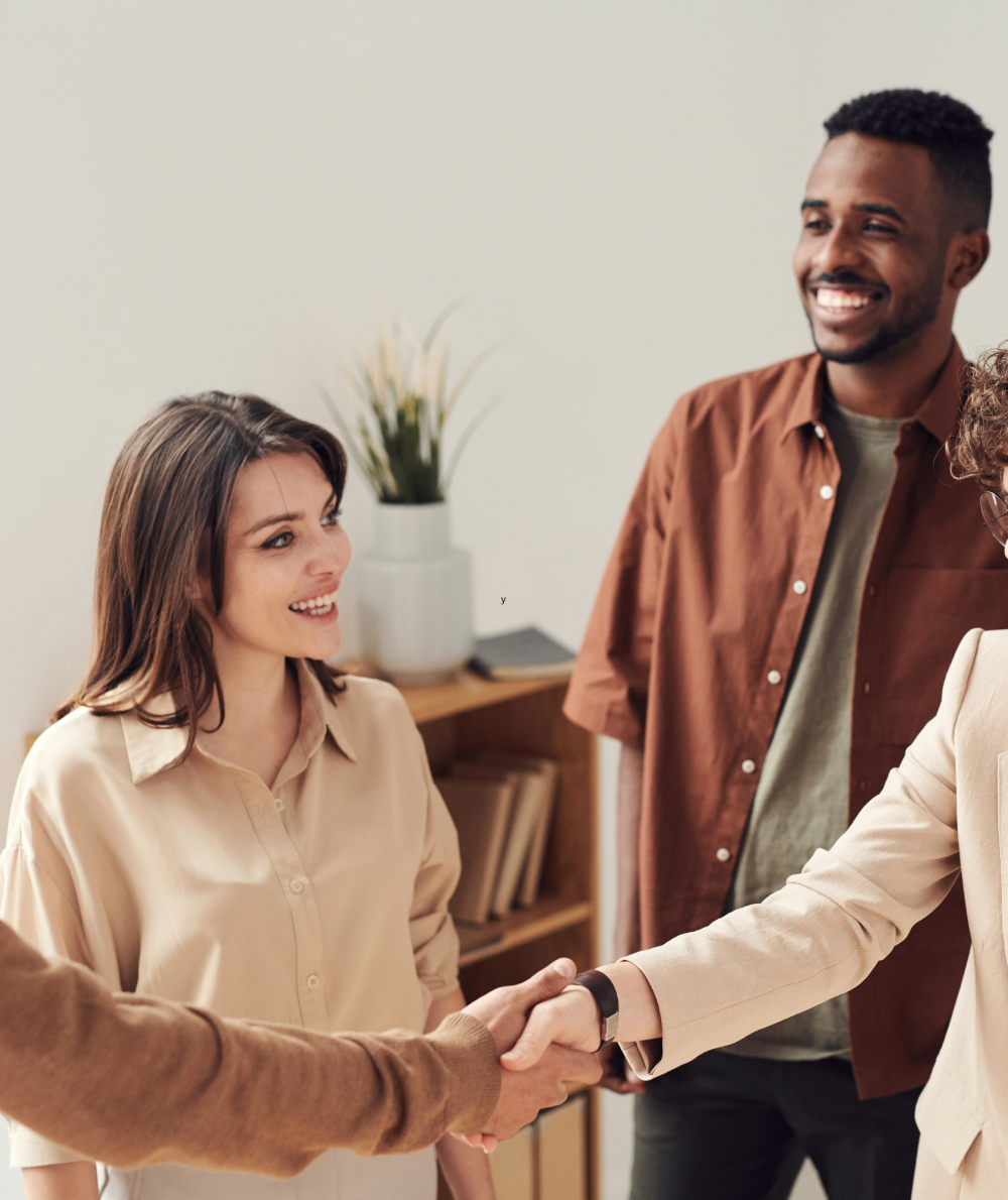 Two professionals shake hands in a job interview while a group watches