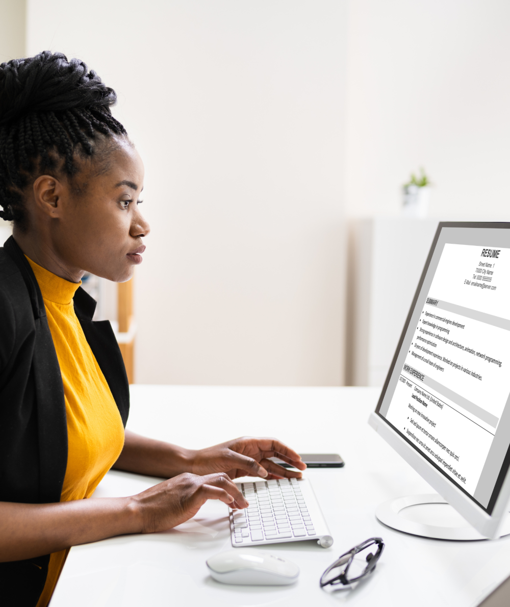 A woman works on her resume on a computer screen at a desk