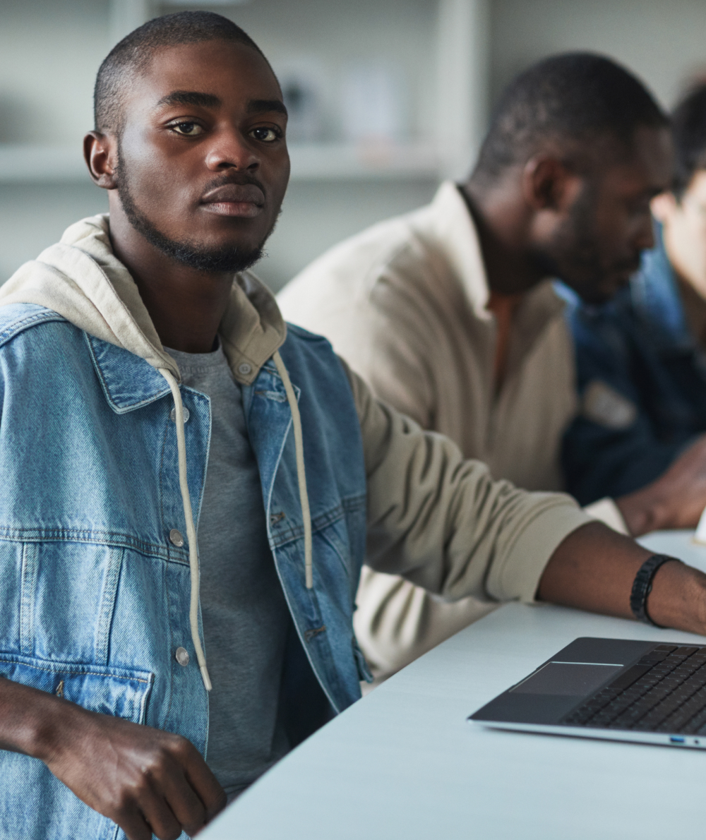 A male student does work at a desk on his laptop 