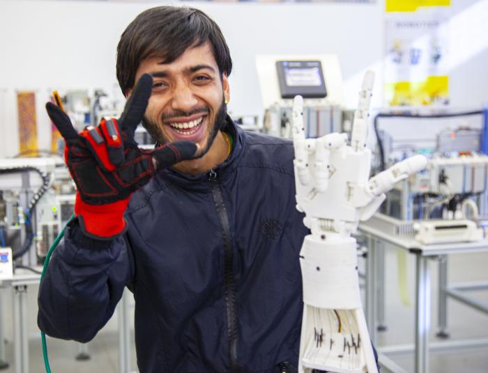 An advanced robotics student demonstrates with the robotic arm