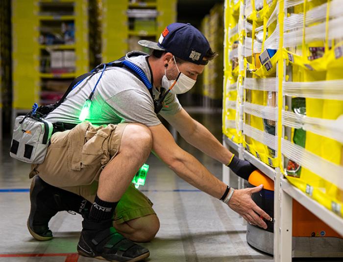 An amazon worker inspects shelves in a warehouse