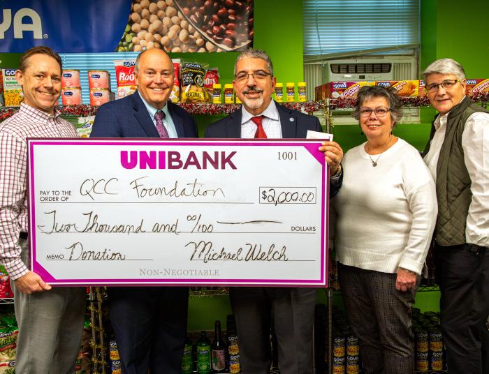 Dr. Pedraja, President of QCC and donors hold up a large check