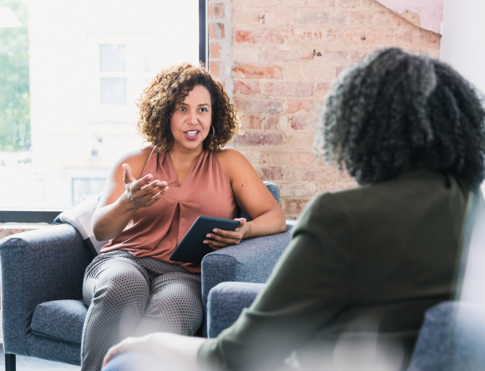 A woman counsels another woman in an office