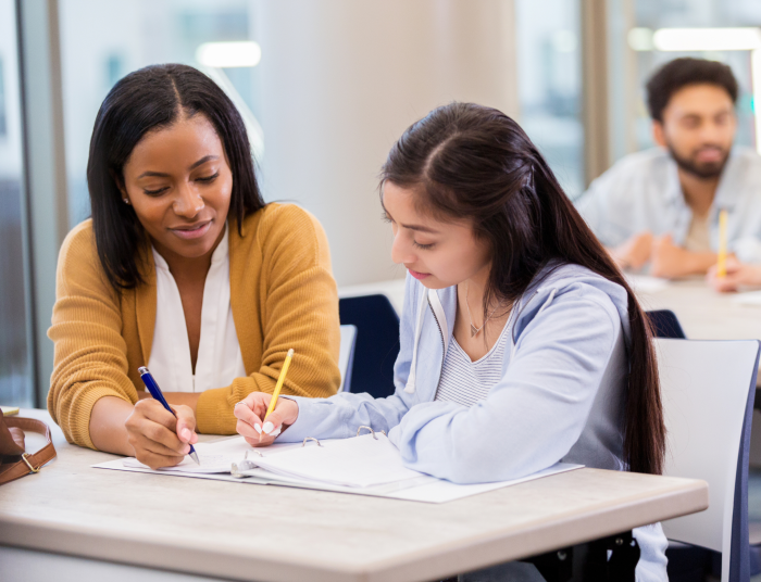 An advisor works with a high school student on some documents