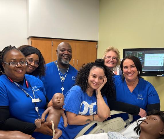 Day and evening practical nursing students with a birthing simulation manikin.