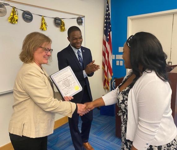 A student receiving their pre-apprentice certificate from Laura Lee and Kwesi Foster