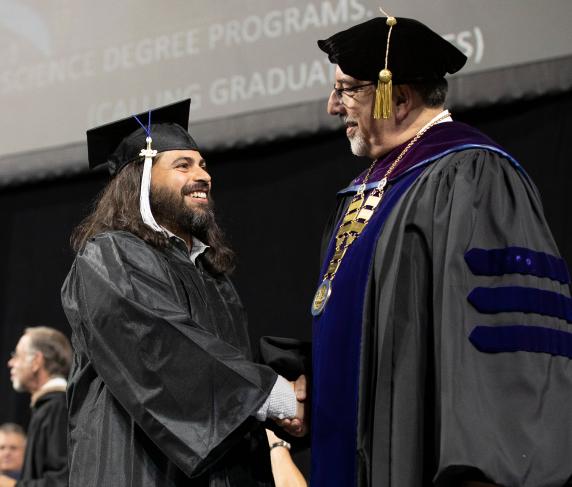 Dr. Luis Pedraja congratulating a student