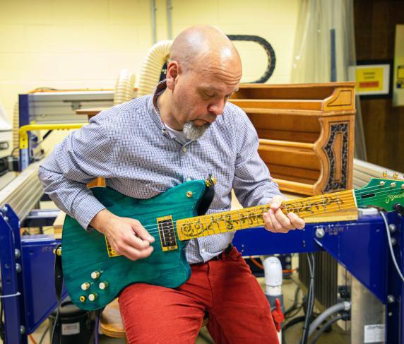 Professor of Music Jose Castillo playing the guitar that Marc Bolduc created for his manufacturing capstone project