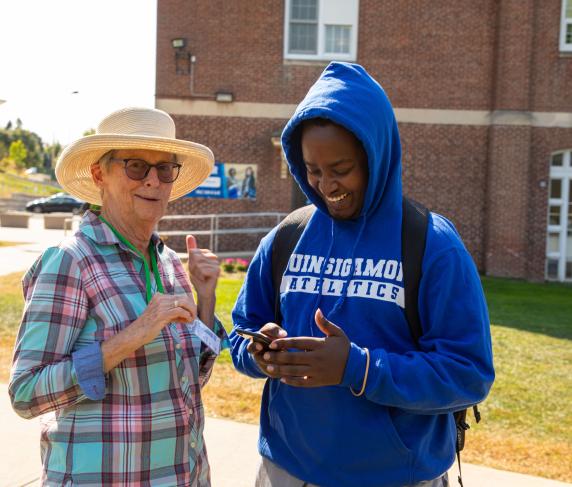 A volunteer from Third Act Massachusetts helps a QCC student register to phone with their phone.