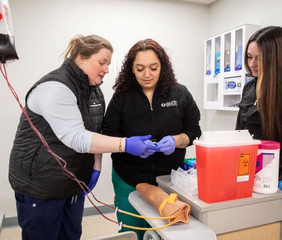 Associate Professor of Medical Assisting Cheryl DeCoff (left) guiding students in the medical assistant apprenticeship degree program.