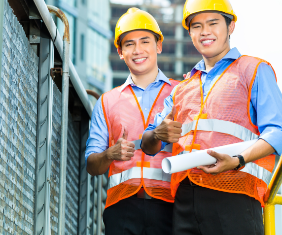Two men in construction gear look at the camera