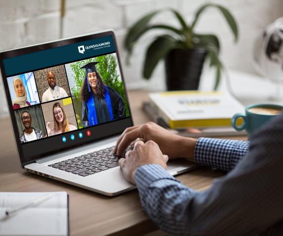 A student watches a computer screen while a group of diverse students chat in a zoom meeting 