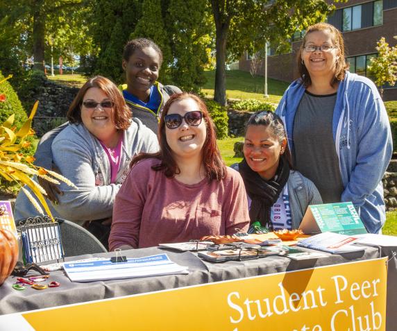 Various students recruit for the Student Peer club on the campus quad during the autumn Club Fair