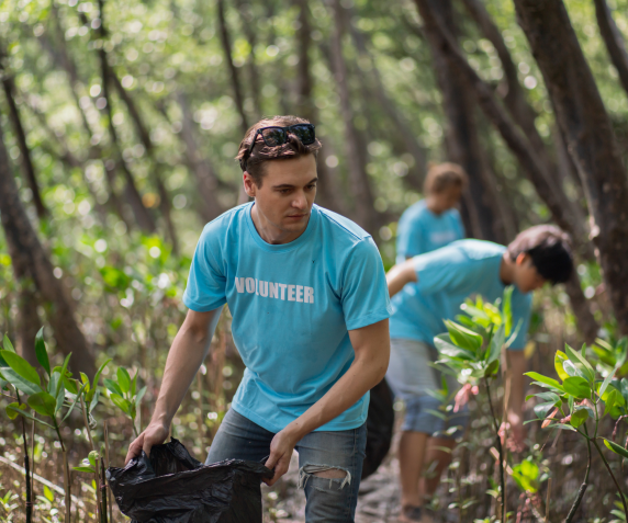 A man volunteers in a wooded area