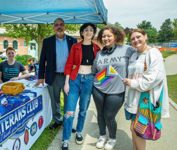 Students and the President pose for a picture in front of the Veteran Affairs booth on the lawn at QCC’s main campus