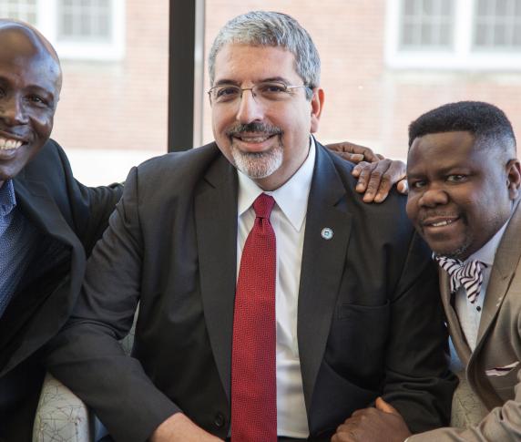 The president and two male students pose together in the Quest Center