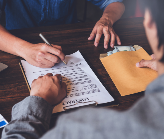 Two people sit at a desk and sign a contract