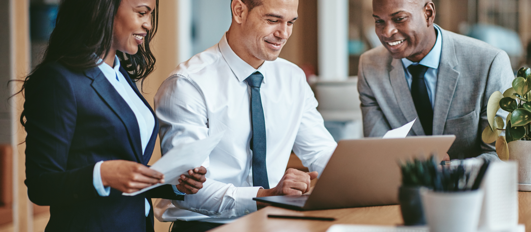 A group of three professionals discuss a document in an office setting