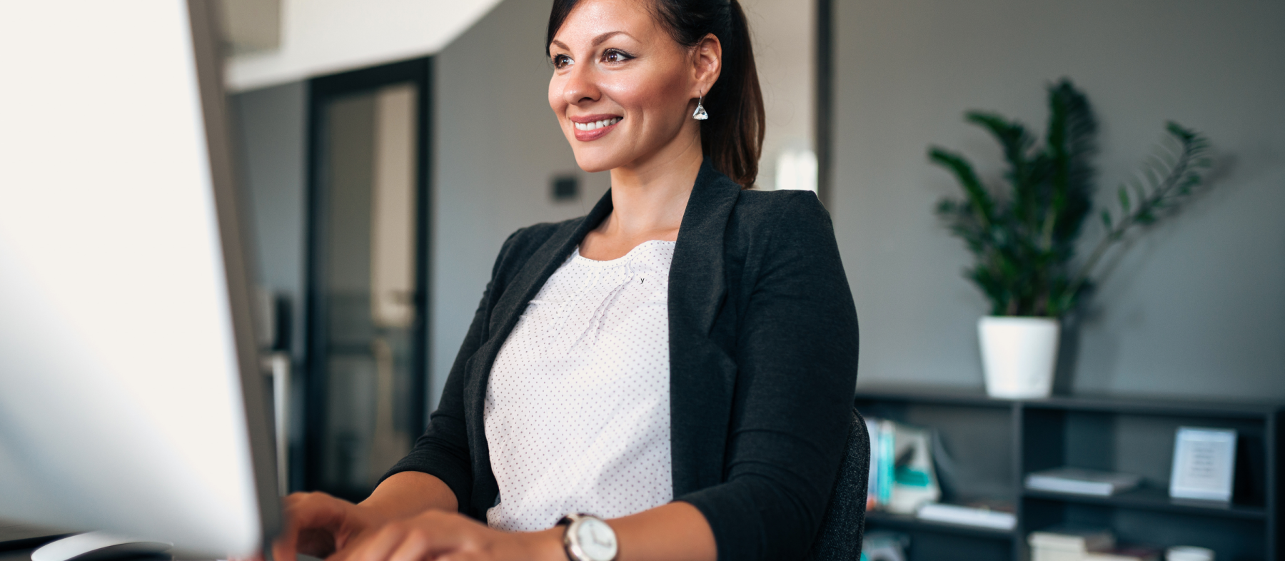 A woman types at a computer desk