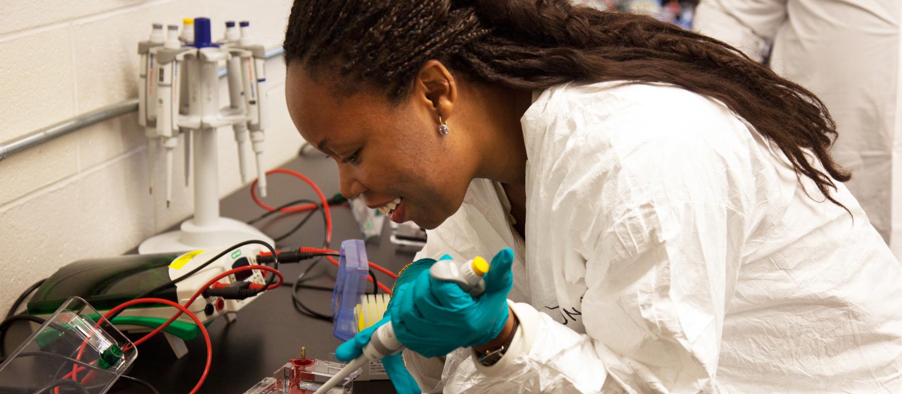 A QCC student uses a pipette in a science lab