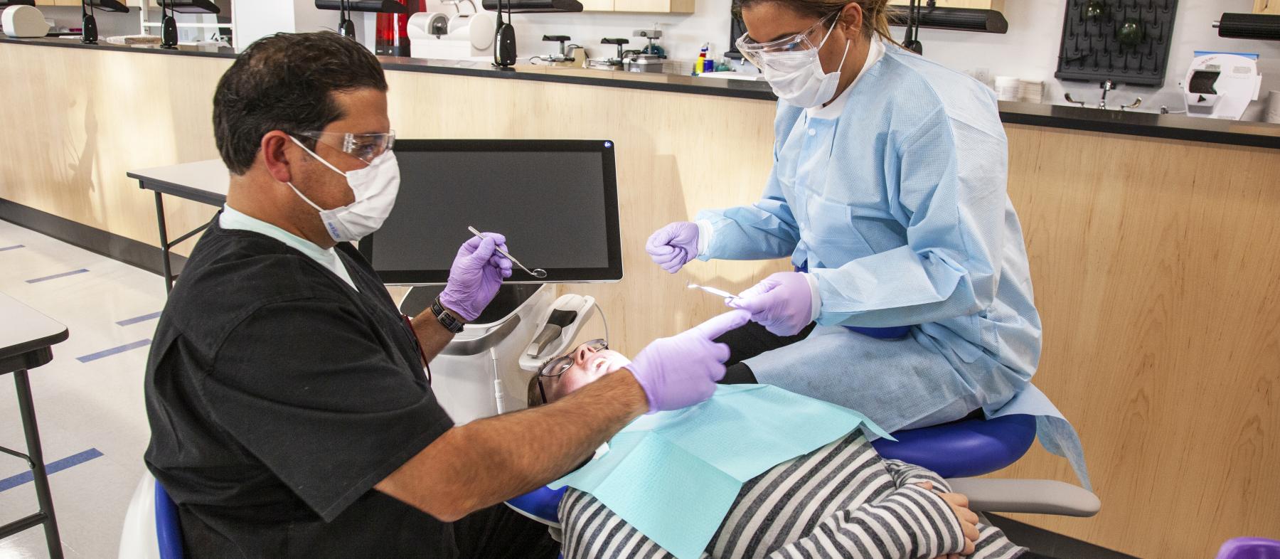 Two dental students attend to a patient