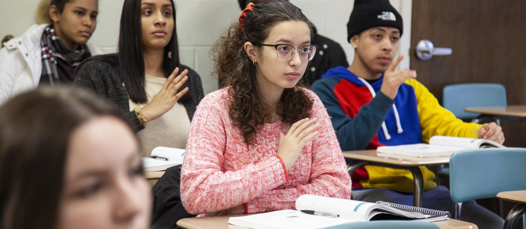 A class full of students practices sign language.