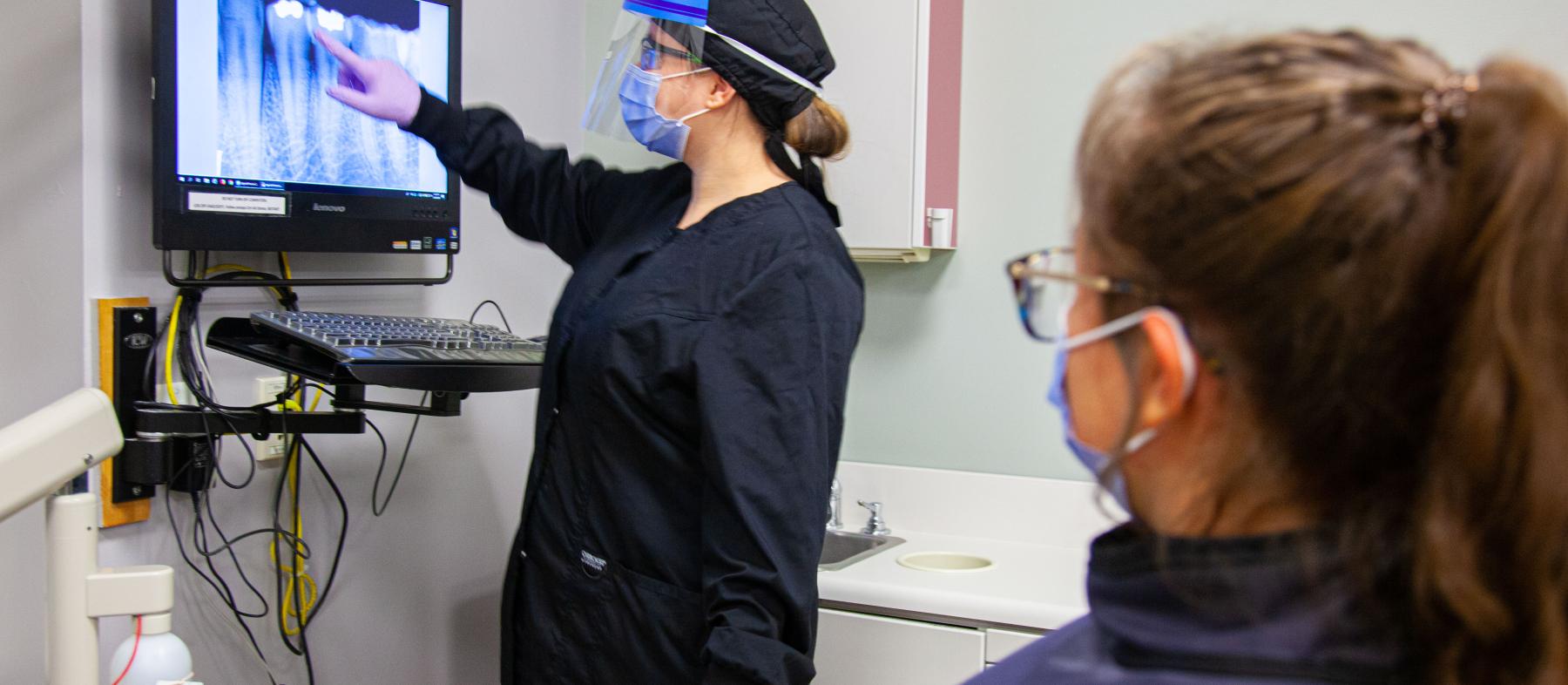 A lab tech shows a tooth x-ray to a patient