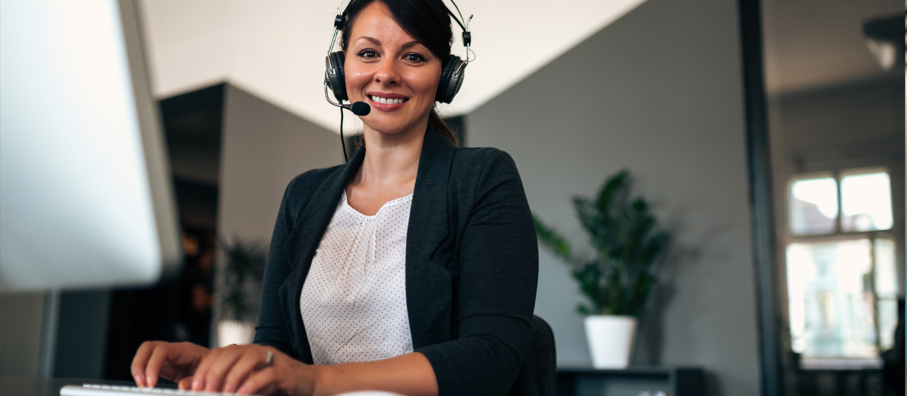 A woman with a headset works on a computer