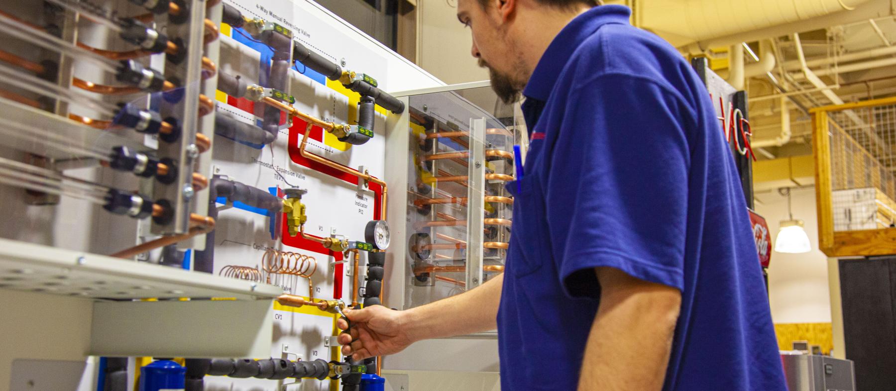 A student works with a HVAC setup in a lab