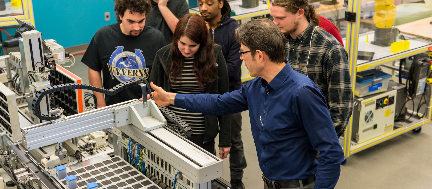 A professor shows advance manufacturing equipment to a class