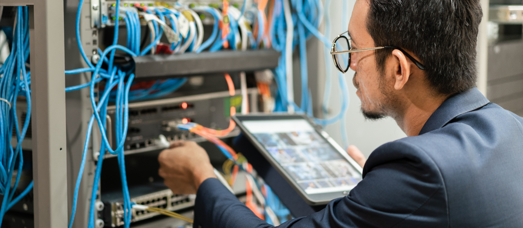 A man configures wires on the back of a server tower