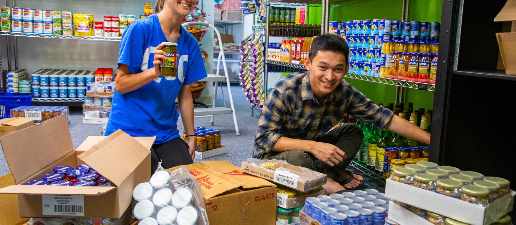 Two students volunteer to stock shelves in the food pantry