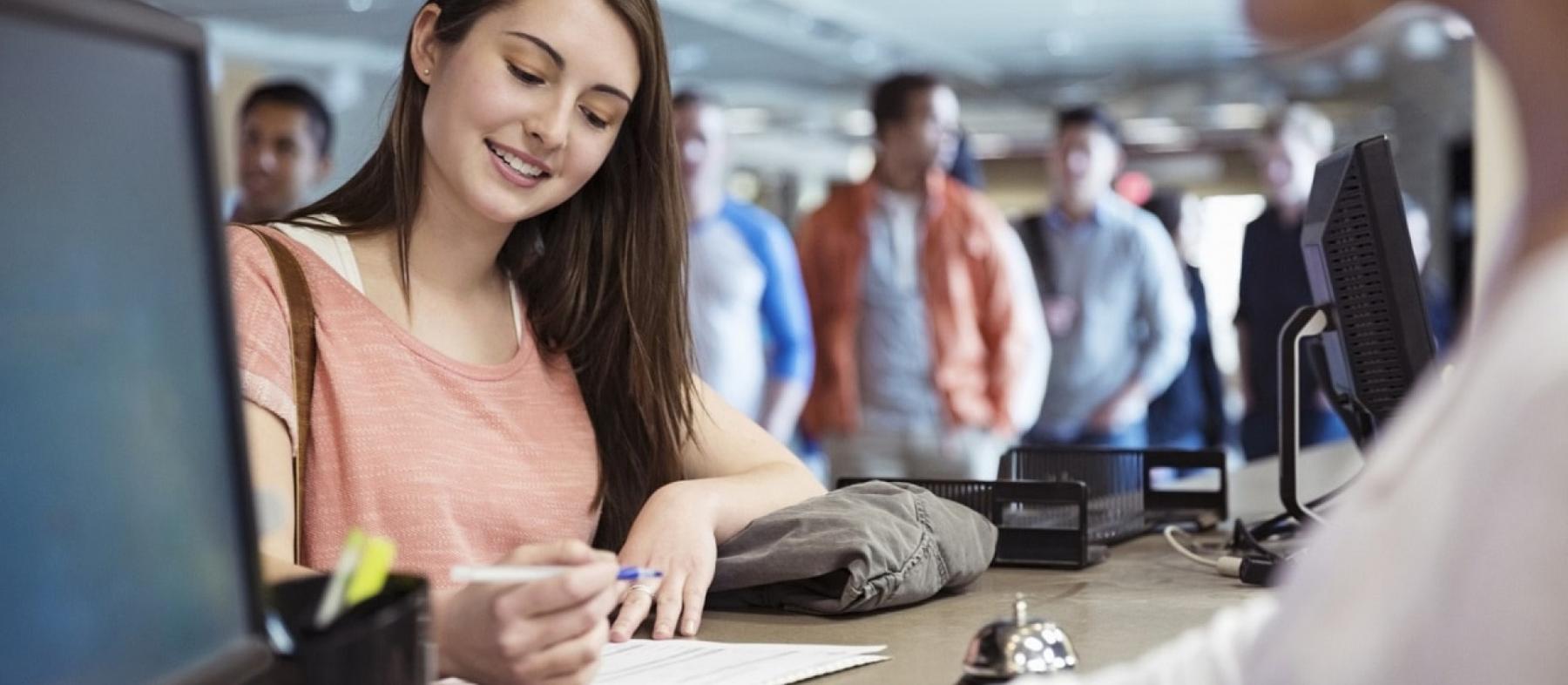 A female student does paperwork at a check-in desk