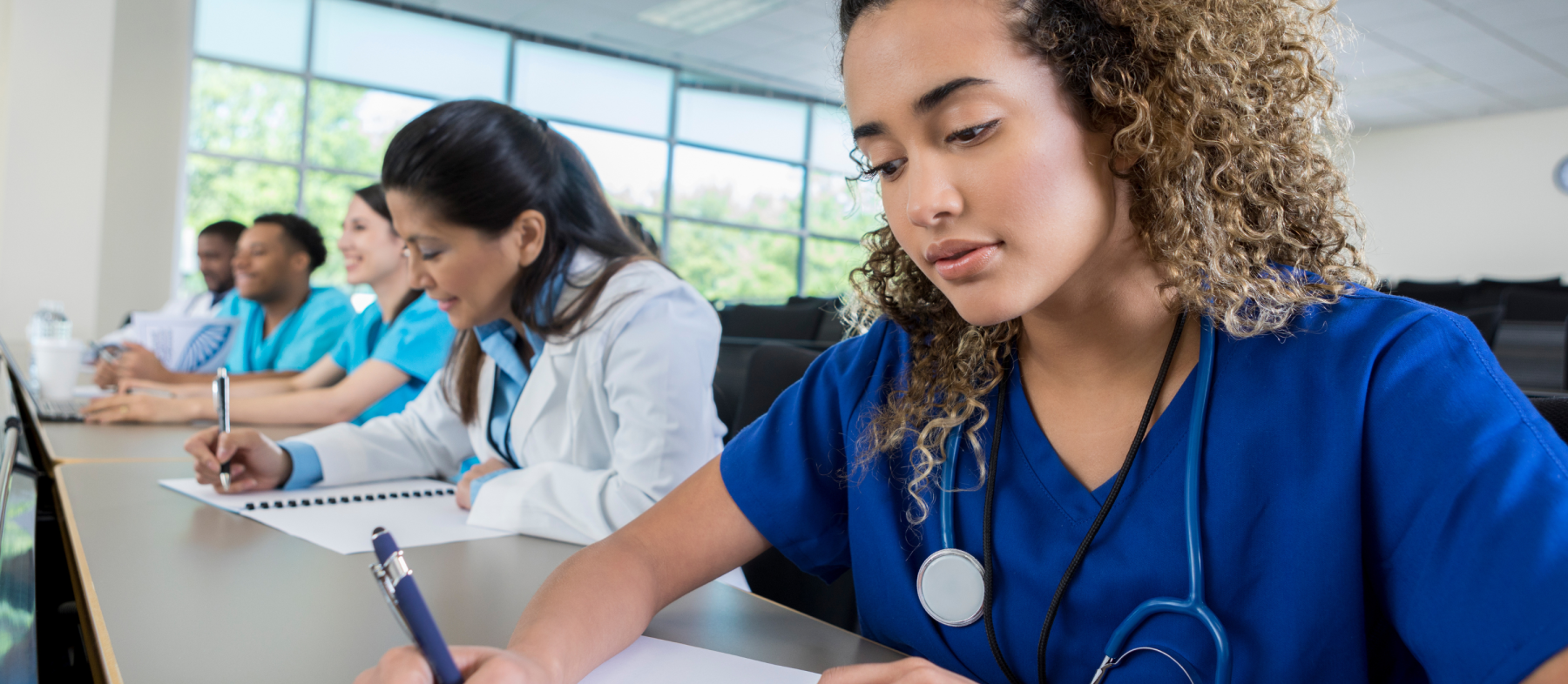 Nurses write in notebooks in a class