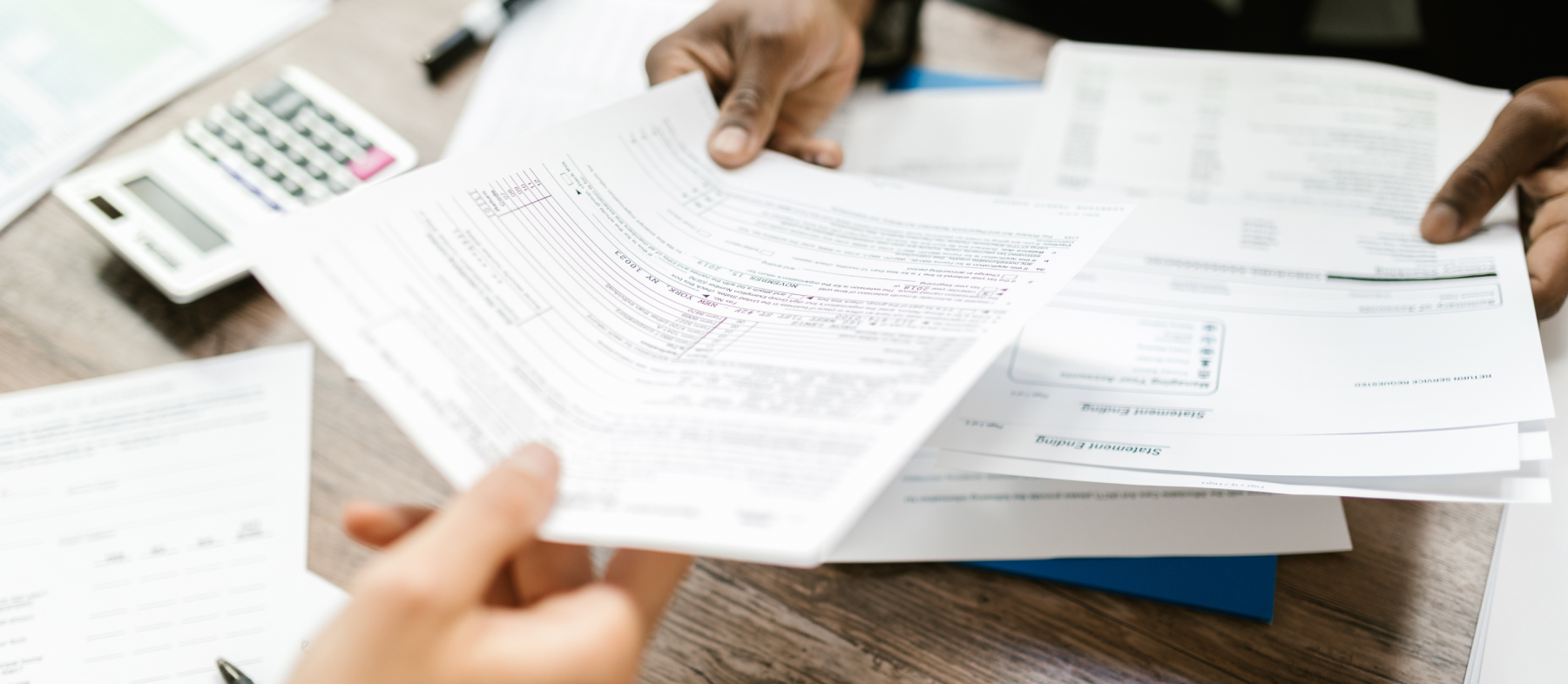 A tax document being handed to a second person across a desk