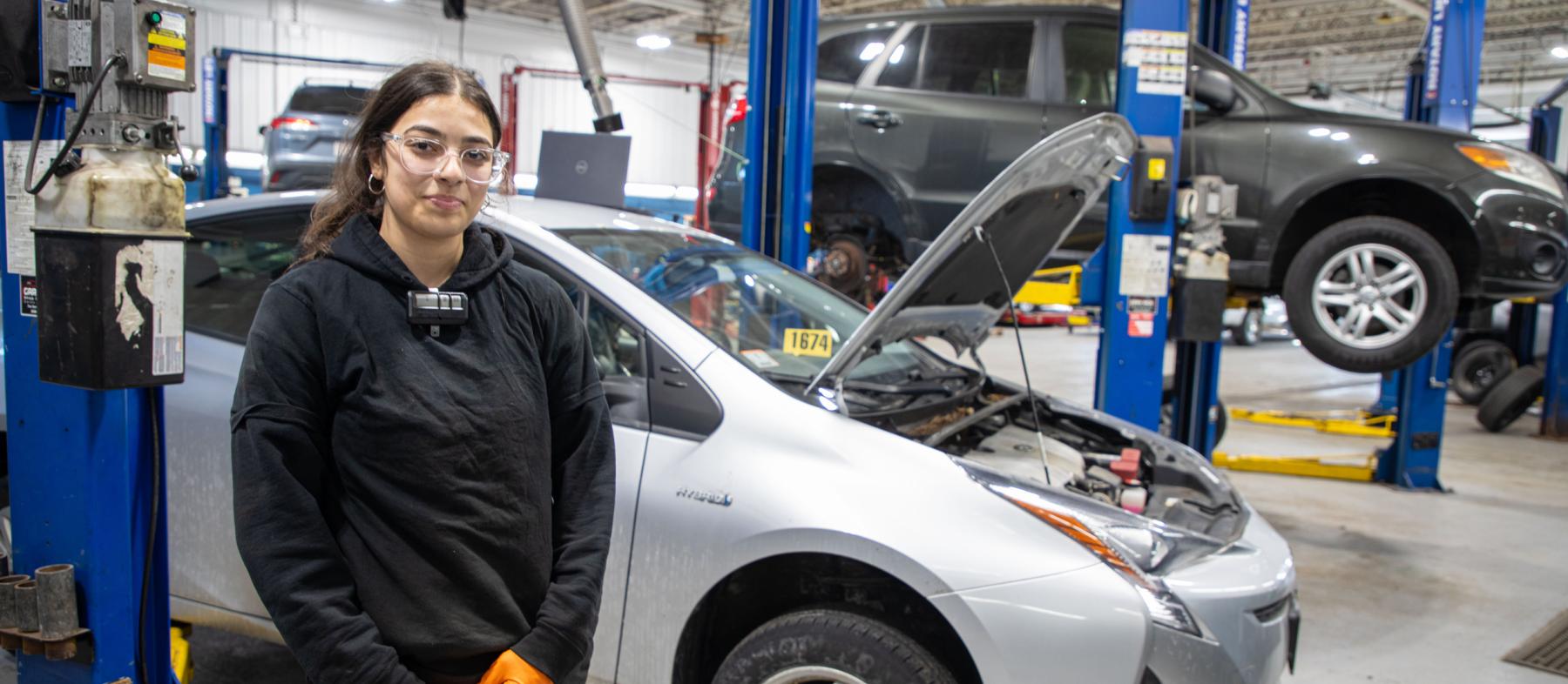 A QCC student works on cars in a garage.
