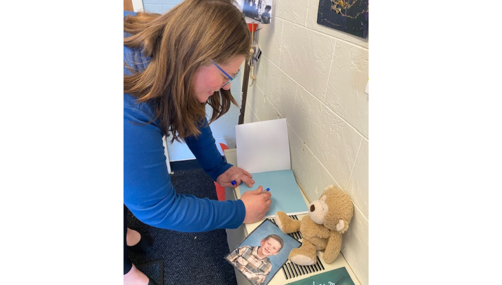 Enrollment Counselor Caitlin Bogue signs a copy of her book "Everett's Washing Machine" for the Children’s School: Early Childhood Education Lab School