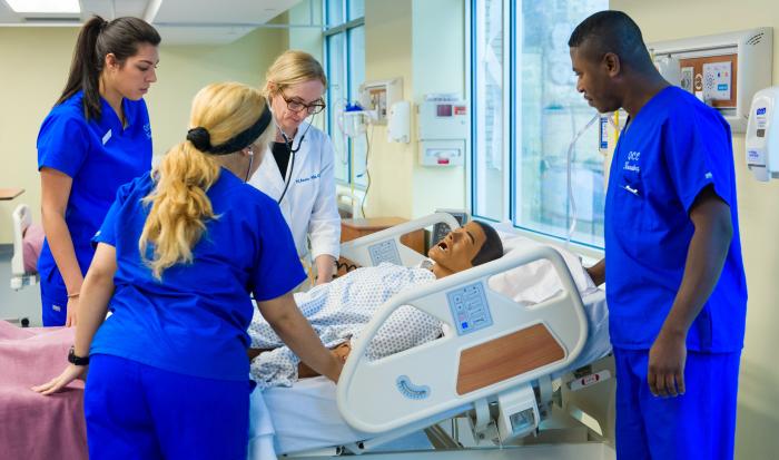 Nursing students work on a realistic nursing manikin. Nursing students work on a realistic nursing manikin.