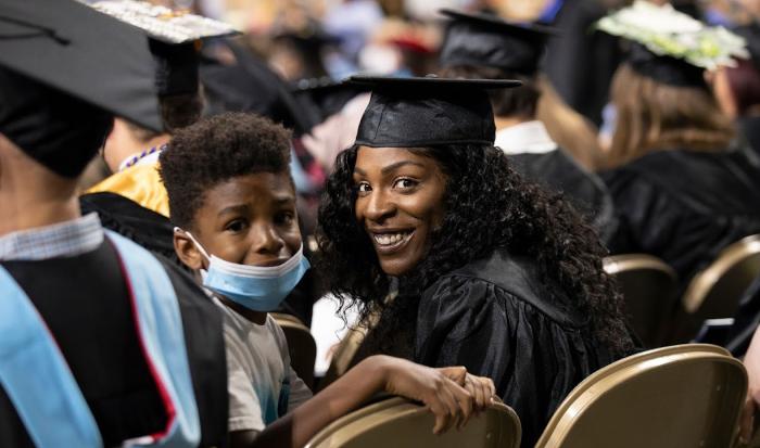 A mother holding her son wait in the seats at commencement A mother holding her son wait in the seats at commencement